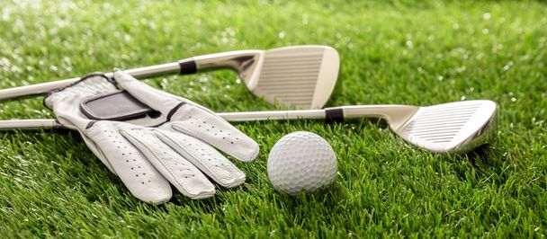 Golfuitrusting, stokken, handschoen en golfballen op groene baan gazon, close-up uitzicht, banner. Golfsport en clubconcept - Foto, afbeelding