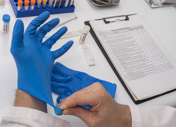 Enfermera colocando guante de látex para analizar resultados positivos de la prueba de covid-19 de personas infectadas, Imagen conceptual - Foto, imagen