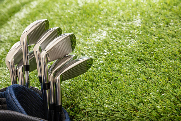 Golf sticks set in a bag on green course lawn, shiny stainless steel, close up view. Golfing sport and club concept, copy space. - Zdjęcie, obraz