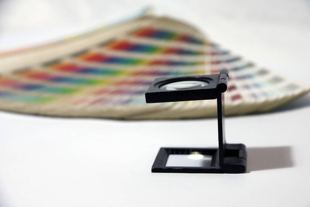 Verre grossissant carré noir et catalogue de palettes d'échantillons de couleurs arc-en-ciel, livre d'échantillons de couleur isolé sur fond blanc.  - Photo, image