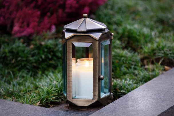Linterna de tumba de metal con vela encendida sobre una tumba - Foto, imagen