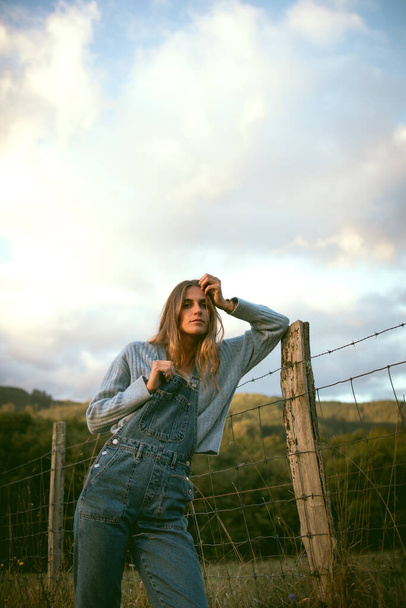 Girl in the woods wearing denim overalls and a cowboy fedora hat. Autumn vives. - Fotoğraf, Görsel
