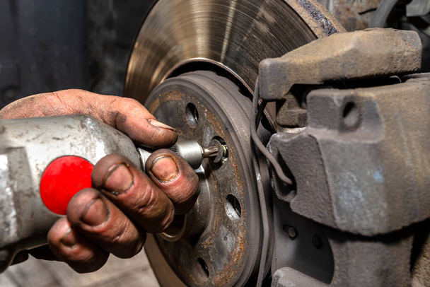 Desaparafusar o disco de freio antigo do carro com uma chave de fenda pneumática. - Foto, Imagem
