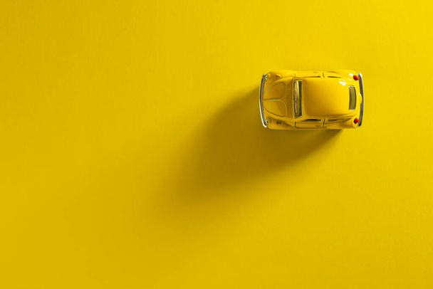Top view of a Yellow toy car on a Yellow background with long and side shadow. - Foto, imagen