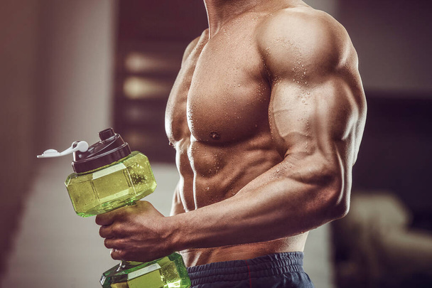 Fitness man in gym drinking water after workout. Fitness and bodybuilding healthy background. Caucasian man doing exercises in gym. Water bottle and supplements nutrition concept - Photo, Image