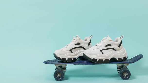 A pair of high-soled sneakers on a blue skateboard. - Fotó, kép