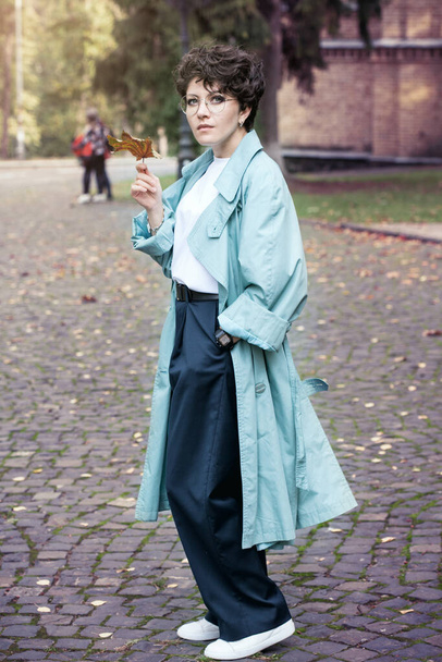 Krásná brunetka kudrnaté vlasy v mátovém plášti procházky v podzimním parku - Fotografie, Obrázek