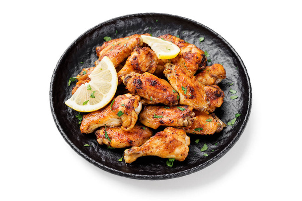 Ψητές φτερούγες κοτόπουλου σερβιρισμένες με διαφορετικές σάλτσες και λεμόνι. απομονωμένο σε λευκό φόντο - Φωτογραφία, εικόνα