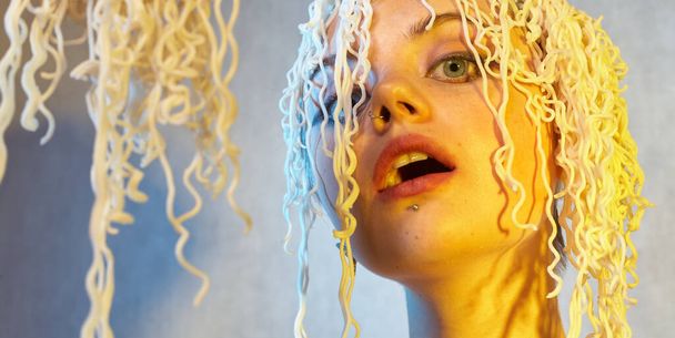 Funny hungry girl with curly noodles on her head. - Photo, Image