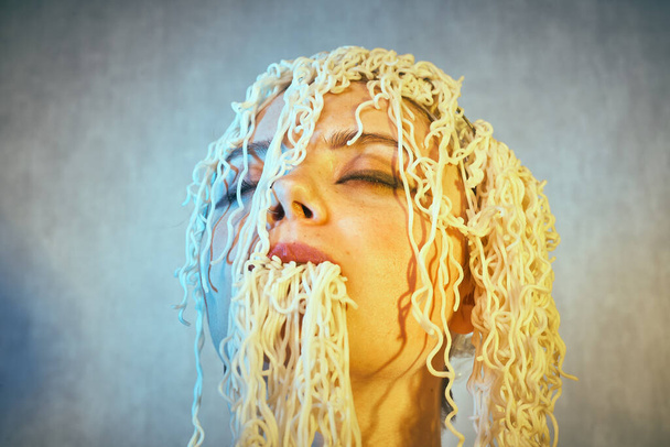 Funny hungry girl with curly noodles on her head. - Photo, Image