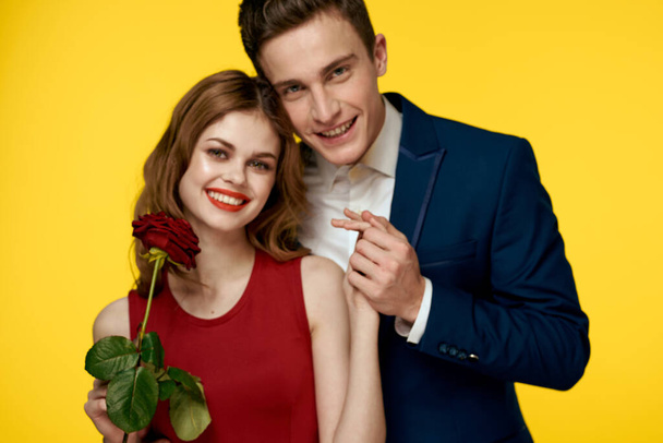 Εραστές άνδρες γυναίκα με κόκκινο τριαντάφυλλο στα χέρια ρομαντικές διακοπές κίτρινο φόντο οικογενειακοί φίλοι. - Φωτογραφία, εικόνα