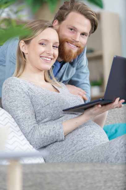pregnant couple using laptop computer - Фото, изображение