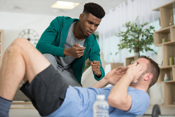 personal trainer encouraging mature man doing sit-ups - Фото, изображение