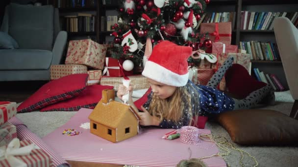 Kleines Mädchen schmückt Lebkuchenhaus - Filmmaterial, Video