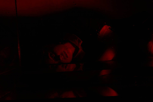 Kamala muotokuva nuoresta tytöstä kauhuhuoneessa, jossa on punainen valo. - Valokuva, kuva