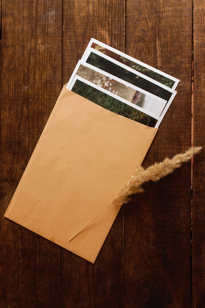 fotos são fechadas em um envelope bege, localizado em uma mesa de madeira marrom - Foto, Imagem