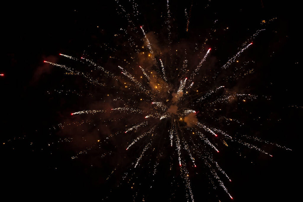 Fekete háttér, arany sugarak és szikrák szétszórt tűzijáték. - Fotó, kép