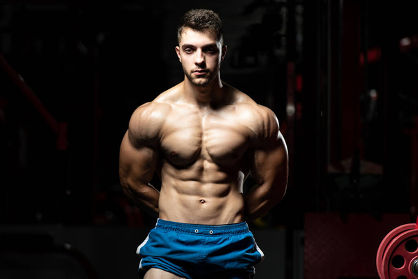 Handsome Man Standing Strong In The Gym And Flexing Muscles - Muscular Athletic Bodybuilder Fitness Model Posing After Exercises - Foto, Imagem