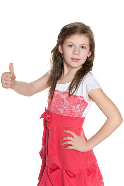 Young girl in red dress holds her thumb up - Фото, изображение