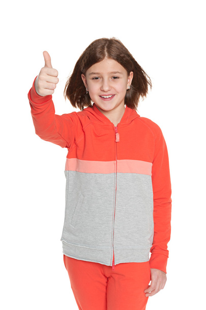 Girl in sportswear holds her thumb up - Photo, image