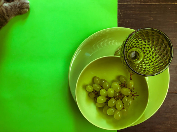 Podawany zalesiony stół z zielonym kieliszkiem do wina na zielonym talerzu z winogronem - Zdjęcie, obraz
