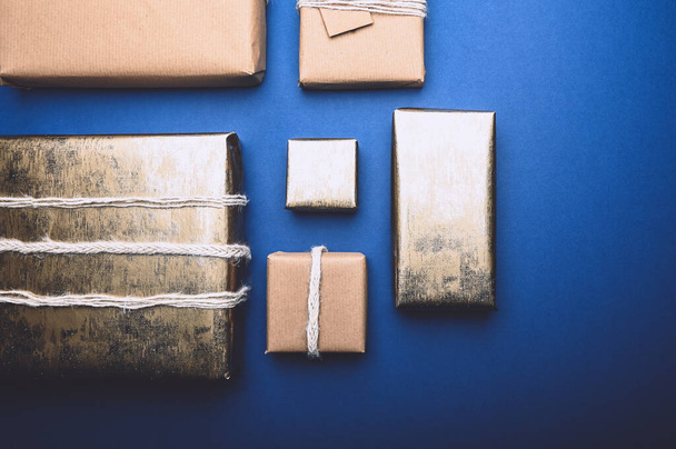 Regalos envueltos en papel marrón reciclado, sobre fondo azul con envoltura de estilo minimalista, vista superior plana - Foto, Imagen