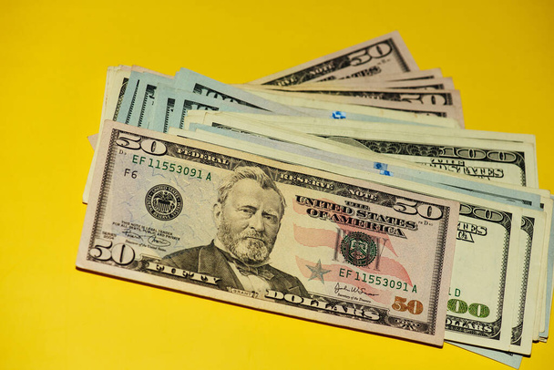 Δολάρια διαφορετικά χαρτονομίσματα. Δολάρια φόντο. Υπόβαθρο διαφορετικών χαρτονομισμάτων δολαρίων ΗΠΑ. Οικονομική έννοια. Χρήματα σε κίτρινο φόντο - Φωτογραφία, εικόνα
