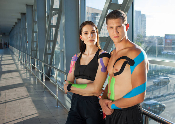 Young sports couple with kinesiological taping posing indoors. - Foto, Bild