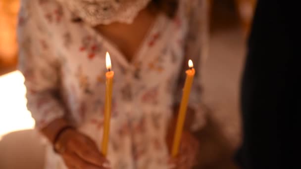 Le mani della donna tengono le candele accese nella chiesa - Filmati, video