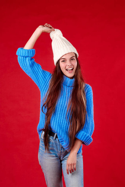  beautiful girl in a sweater and a hat on a red background - Фото, зображення