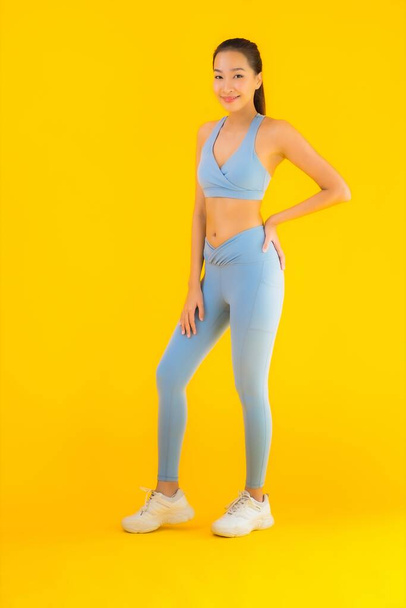 Portrait belle jeune femme de sport asiatique avec des vêtements de sport prêt pour l'exercice sur fond jaune isolé - Photo, image