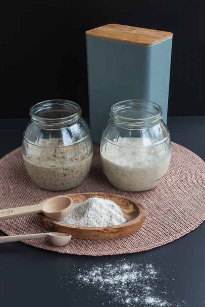 Doğal organik ekşi mayalı başlangıçlar: taze mayalanmış çavdar ve cam kavanozlarda mayalı ekmek yapmaya hazır buğday başlangıçları - Fotoğraf, Görsel