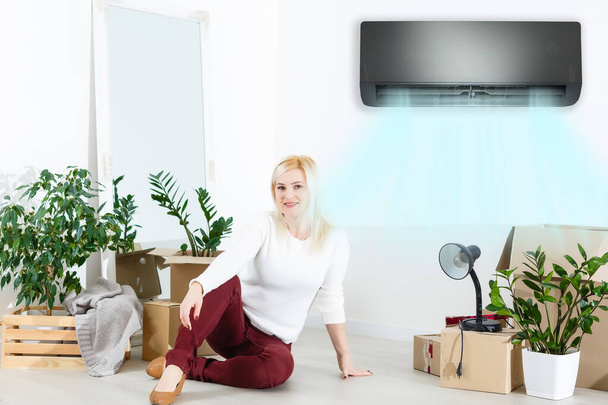 Glückliche Frau, die sitzend frische Luft atmet. Frau in neuer Wohnung unter Klimaanlage - Foto, Bild