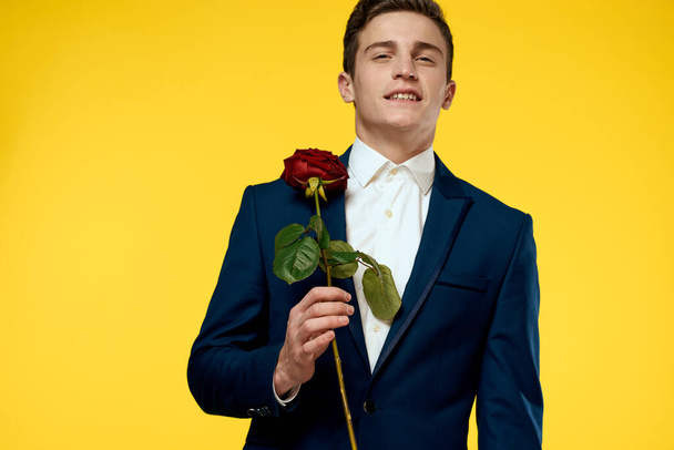 Gentleman in classic suit on yellow background with red rose romance  - Photo, image