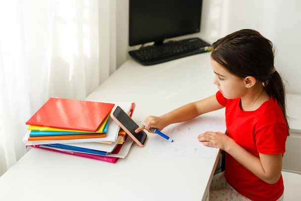 Дистанционное обучение онлайн, маленькая девочка пишет формулы - Фото, изображение