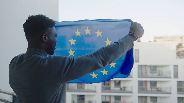 młody atrakcyjny czarny mężczyzna machając flagą Unii Europejskiej - Zdjęcie, obraz