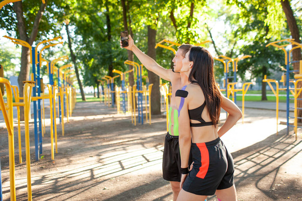 Sports couple with kinesiological taping taking selfie outdoors. - Foto, Imagem
