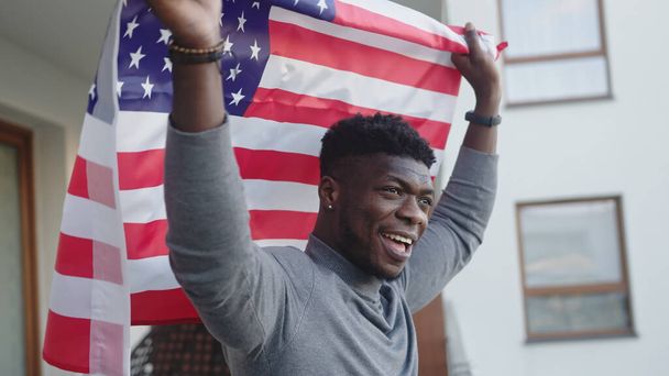 バルコニーにアメリカの旗を持つ黒人アフリカ系アメリカ人 - 写真・画像