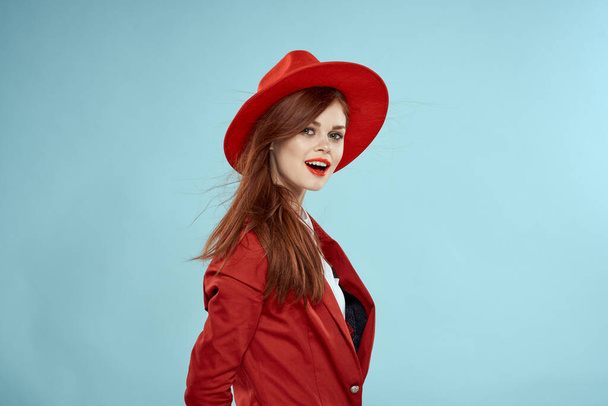 Beautiful woman in red hat jacket red lips long hair charm blue background - Photo, Image