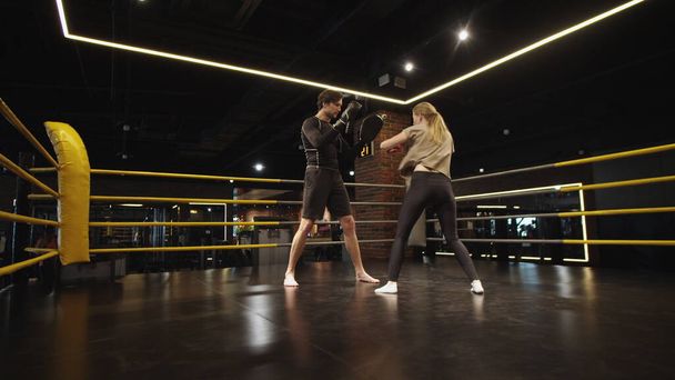 Poważnie wysportowana dziewczyna walcząca z trenerem na siłowni. Trening dla par sportowych w klubie sportowym - Zdjęcie, obraz