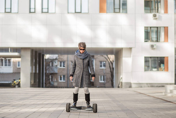 Mode senior vrouw met gyroscooter in de stad - Foto, afbeelding