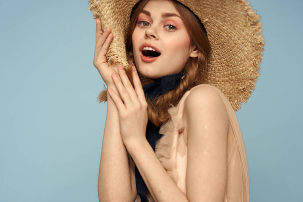 Dziewczyna w słomkowym kapeluszu portret zbliżenie warkocze zabawa rude włosy niebieskie tło - Zdjęcie, obraz