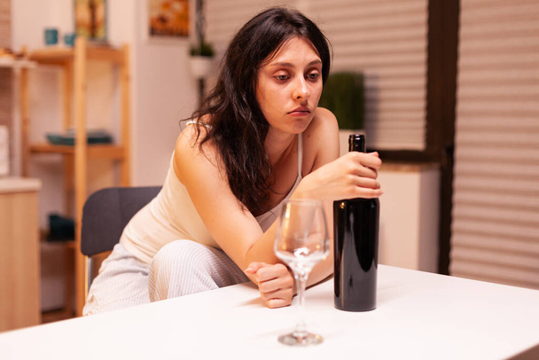 Samotna kobieta trzymająca butelkę czerwonego wina. - Zdjęcie, obraz