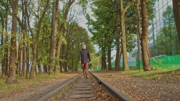 Mladík se sebevědomě přesune ke kameře v parku na trati, stylově oblečený teenager. - Záběry, video