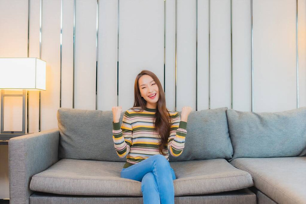 Портрет красивая молодая азиатская женщина улыбка расслабиться на диване в гостиной интерьер - Фото, изображение