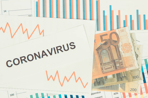 Inscription coronavirus, currencies euro and downward graphs representing financial crisis caused by Covid-19. Risk of global recession around world - Фото, изображение