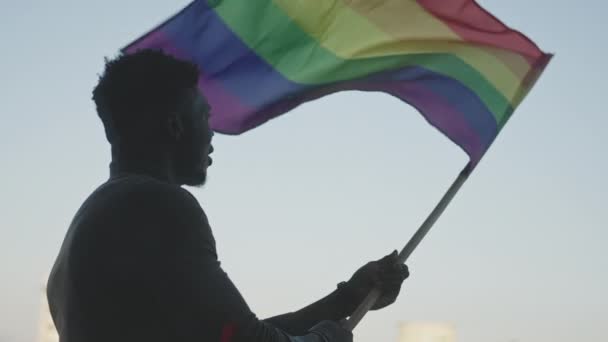 Siyah adam gökkuşağı bayrağı sallıyor. Cinsel kimlik ve eşit tedavi konsepti - Video, Çekim