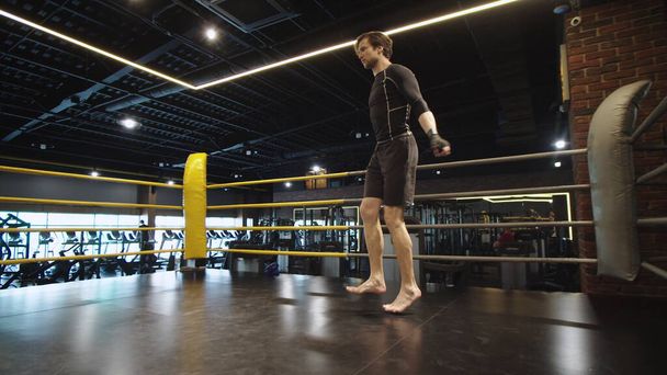 Спортивный спортсмен совершает прыжки в спортивном клубе. Мужские упражнения боксера в тренажерном зале - Фото, изображение