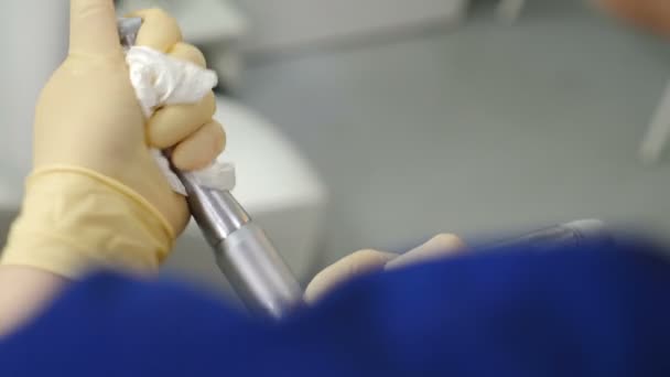Γυναίκα βοηθός από το προσωπικό οδοντιατρικής κλινικής καθαρισμού και απολύμανσης οδοντιατρικών εργαλείων και εγκαταστάσεων. Κοντινό πλάνο με χέρια να κρατάνε τρυπάνια και να βγάζουν χώμα από δυσπρόσιτα μέρη. 4 k βίντεο - Πλάνα, βίντεο