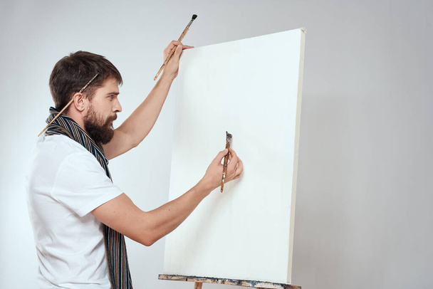 Männliche Künstler Pinsel in den Händen der Staffelei Kunst Hobby Licht Hintergrund Schal um den Hals - Foto, Bild